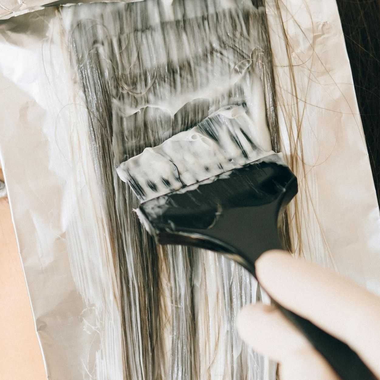 Close-up of hair being dyed with a brush on foil strips.